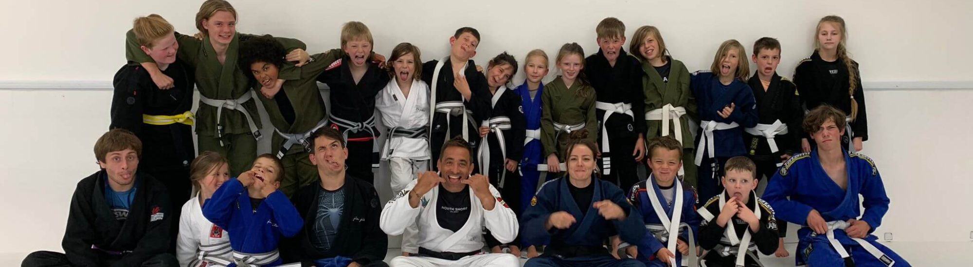 Energised group of North Shore BJJ kids taking a class photo at the club